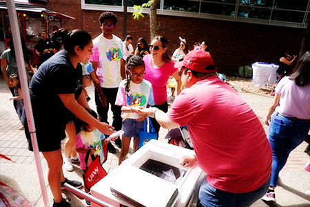 Alumni handing out food to a child