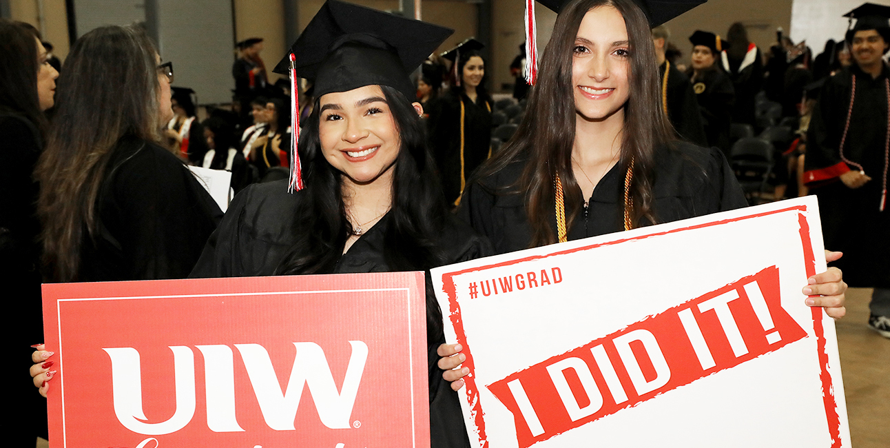 Two students holding graduation signs