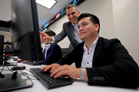 student at a computer, with professor pointing something out