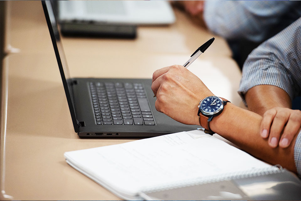 writing on paper next to laptop