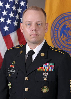 Photo of man in US Army uniform in front of flags