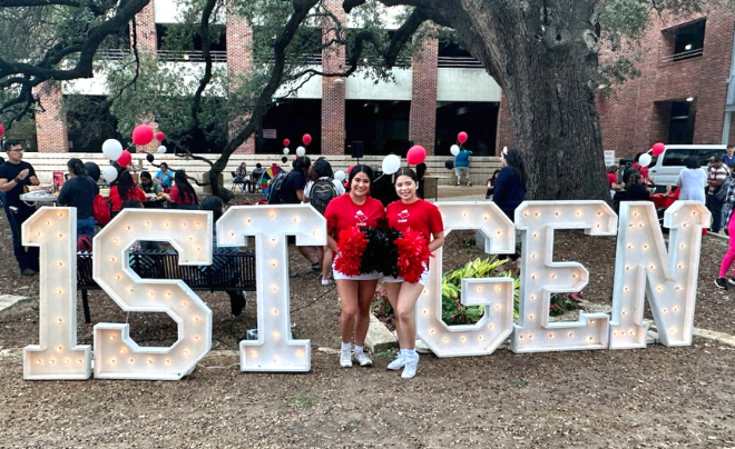 Two first-gen students standing between 1st gen signs