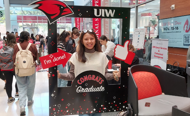 Student posing with a sign that says Congrats Grad