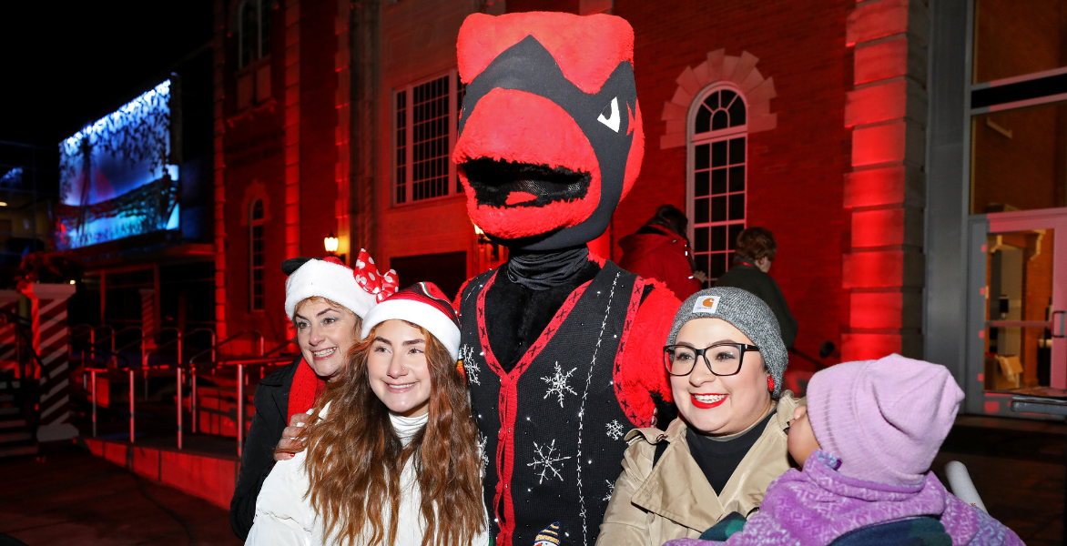 Four people smile with Red the Cardinal