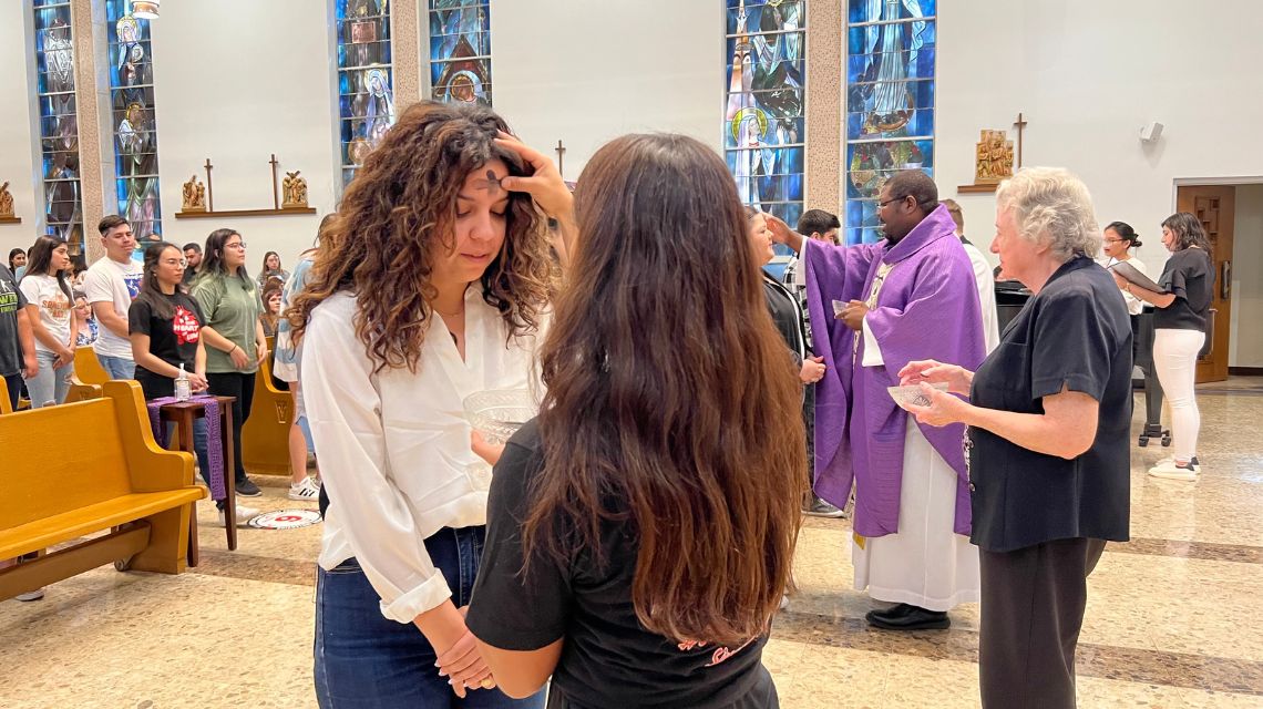 Woman wearing white shirt receives ashes