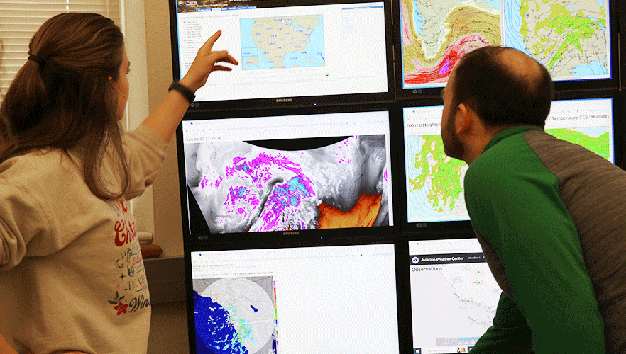 2 meteorology students looking at forecast monitors