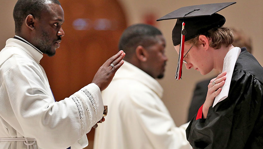 Mass leader praying over graduate