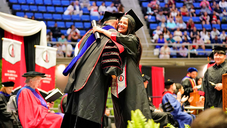 Graduate hugging Dr. Thomas M. Evans upon receiving degree