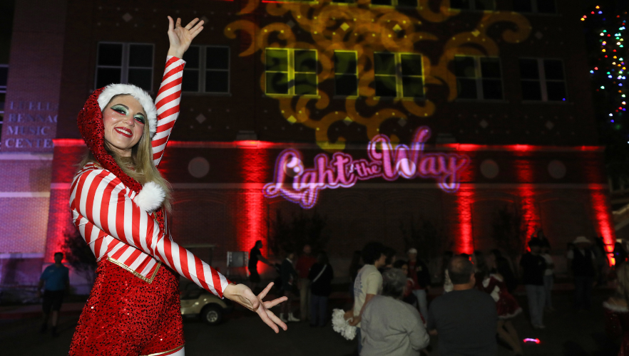 Stilt walker next to Light the Way display