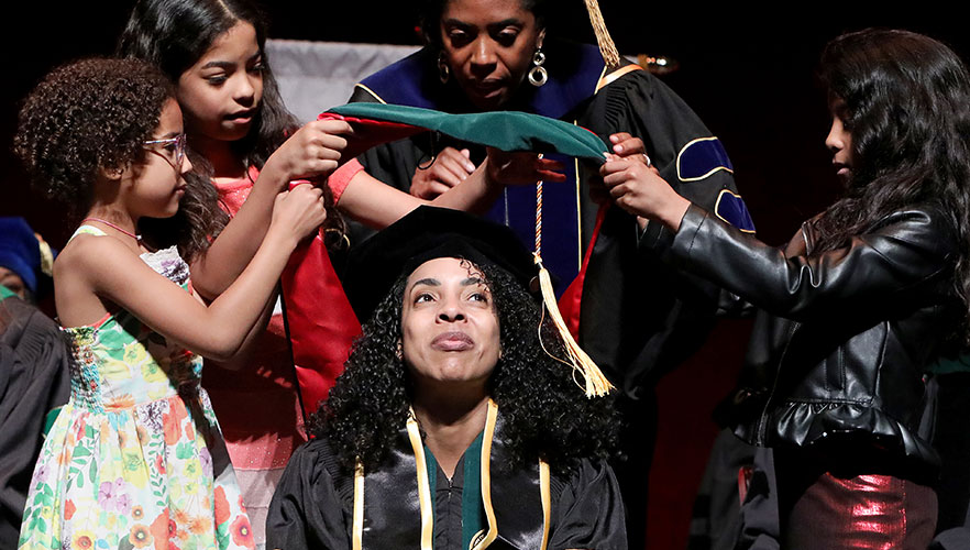 UIWSOM graduate being hooded by children