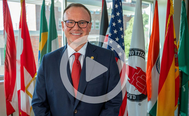 UIW President Thomas Evans in front of international flags
